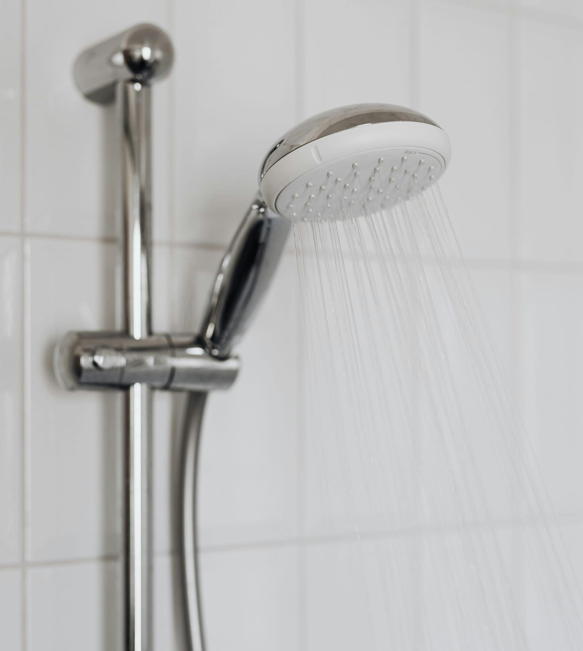 Montiertes Duschsystem mit Glaswand, Duschstange und Brause in einem renovierten Bad.